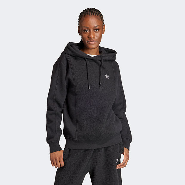 Person wearing a black Adidas hoodie and pants on a white background